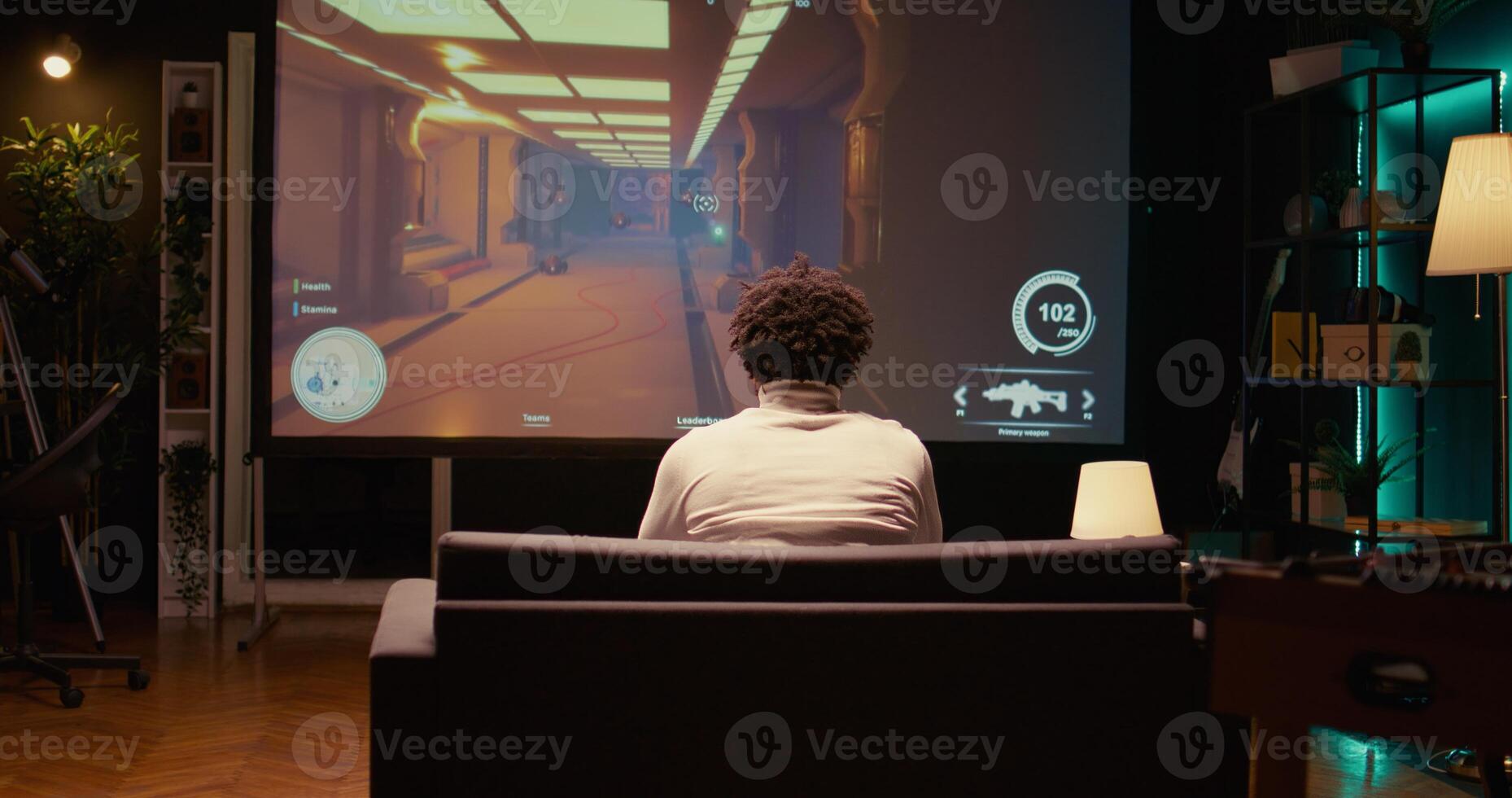 African american man plays first person shooter videogame on ultrawide smart TV with gun shooting at enemies. BIPOC gamer enjoying PvP online multiplayer game with players competing against each other photo
