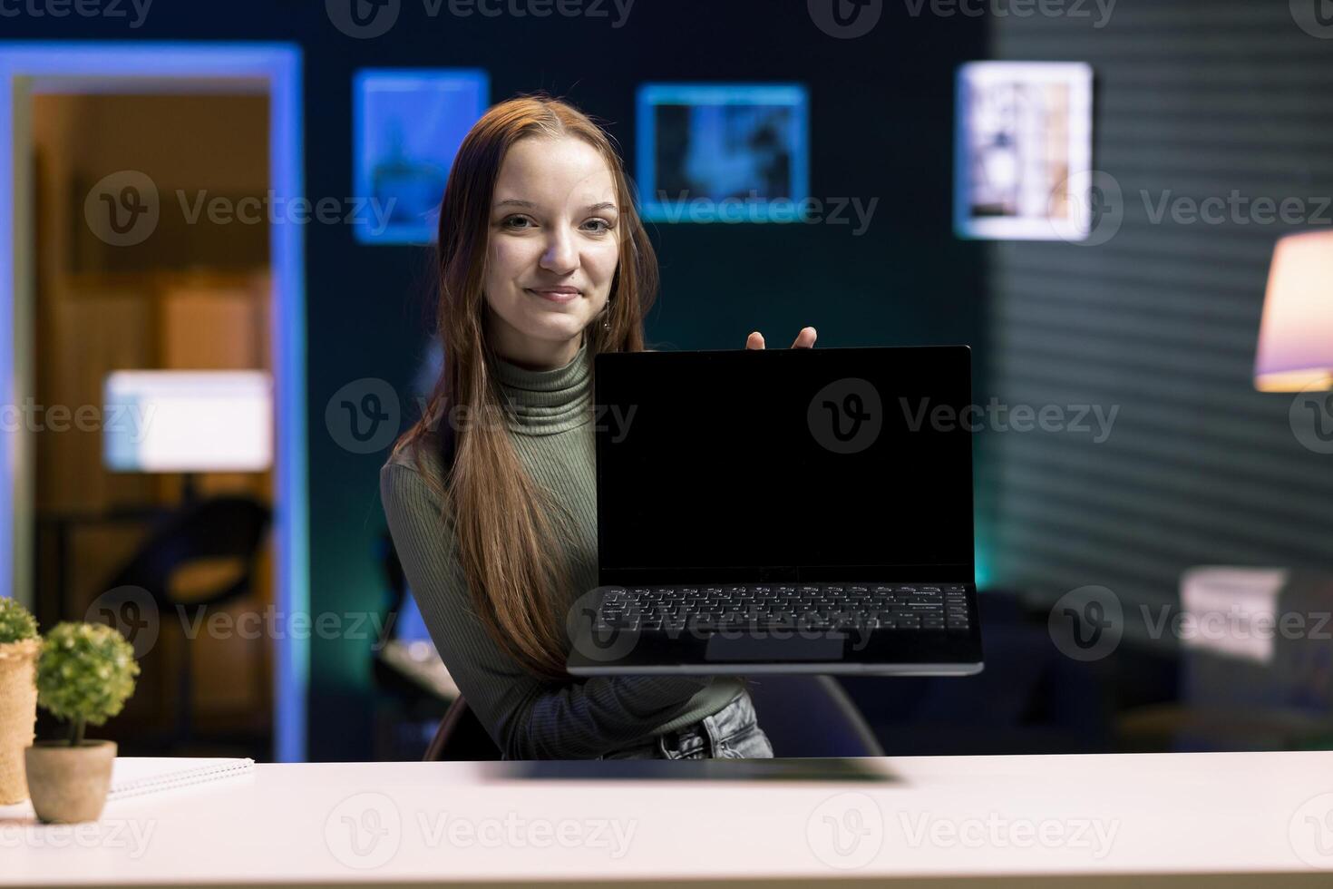 Smiling young entertainer presenting laptop from brand sponsoring , urging subscribers to purchase it. Cheerful media star does influencer marketing by advertising digital device to audience photo