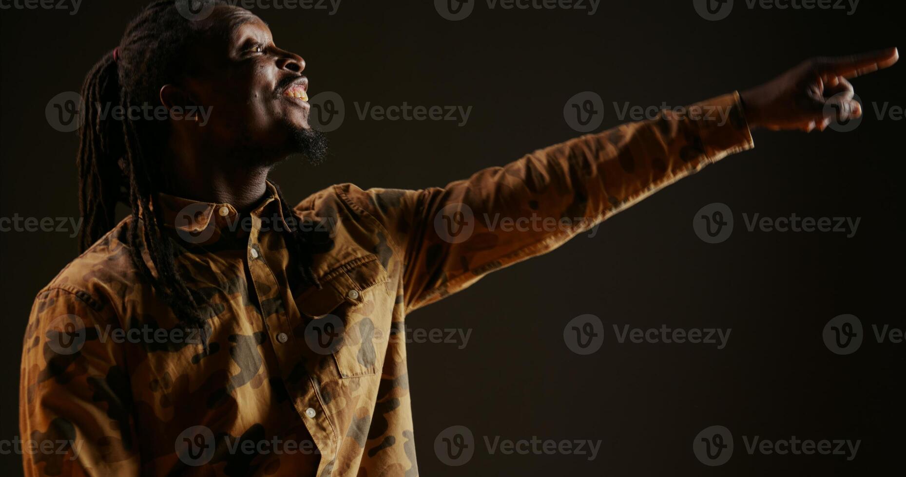 African american guy cheers for someone in studio, supporting and encouraging person over black background. Adult feeling confident and optimistic, celebrating victory and triumph. Handheld shot. photo
