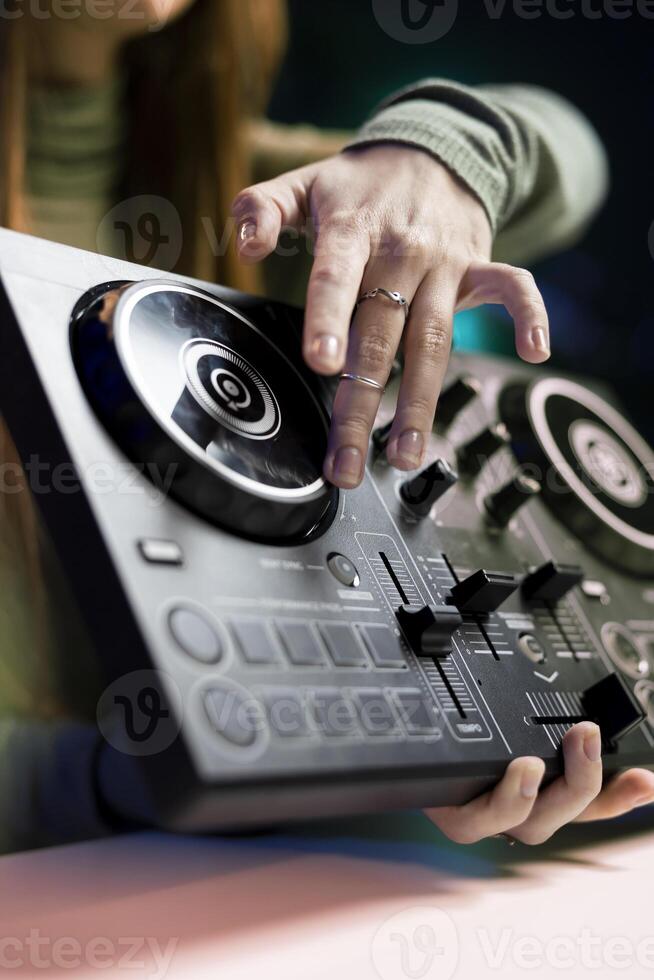 Girl filming mixing tutorial in home studio, showing examples of sampling on sound controller to viewers, close up shot. DJ showing high tech musical gear to interested fans photo