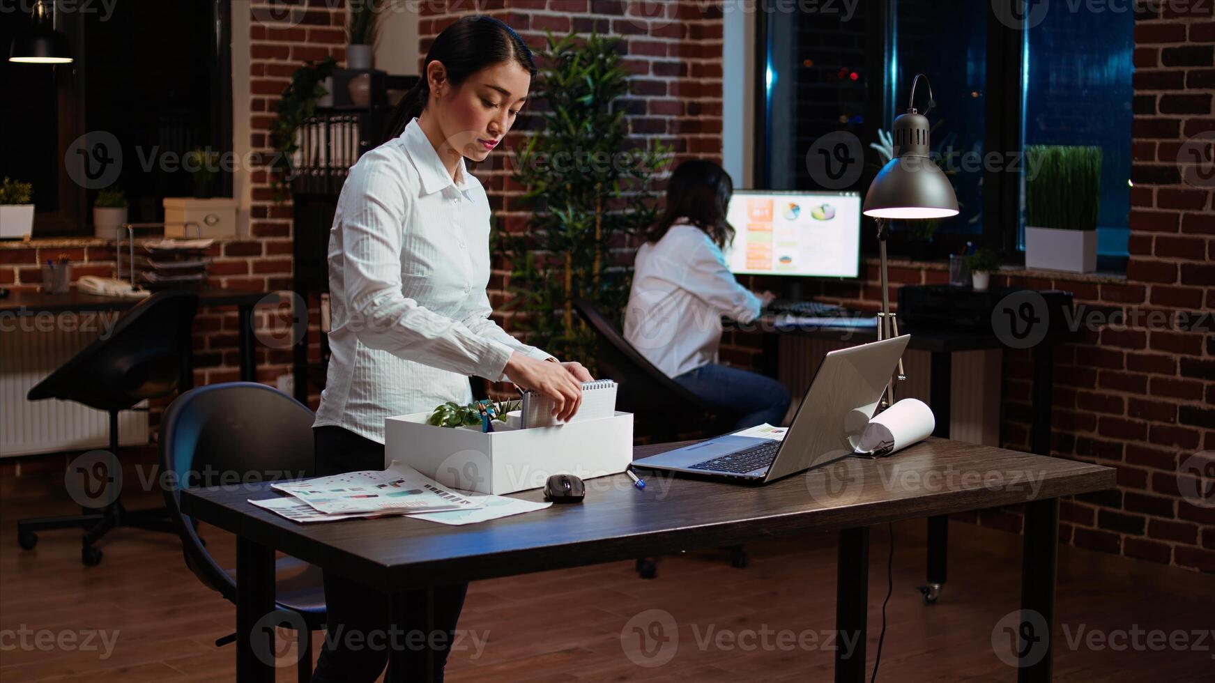 Sad employee packing desk things after quitting job, saying goodbye to colleague. Disappointed employee preparing to leave workplace after accepting another company position, camera A photo