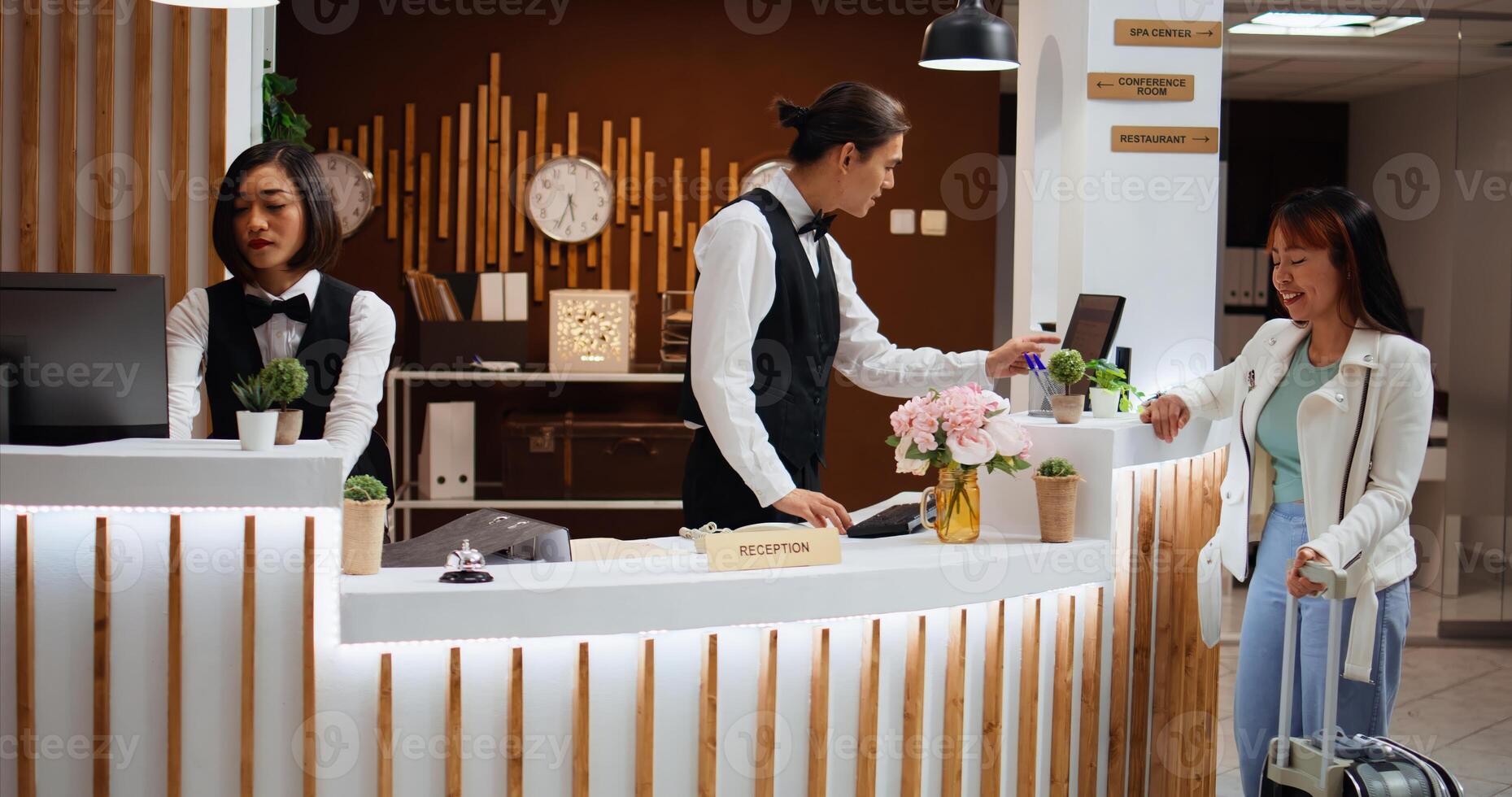 Hotel guest arriving at reception to do check in process, claiming room reservation after long flight. Woman traveler on vacation at five star resort talking to receptionist about facilities. photo