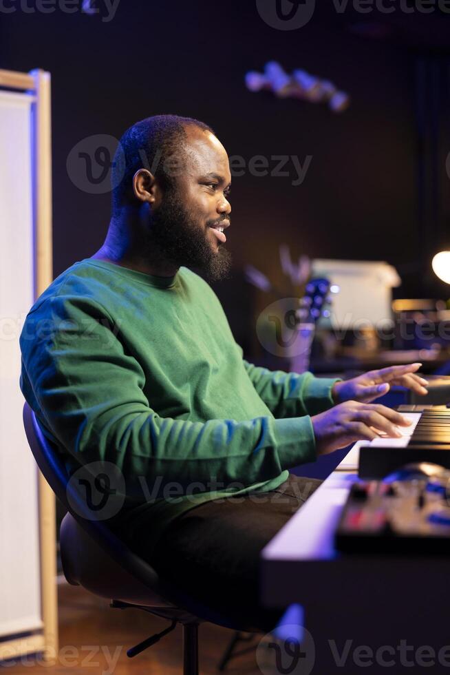 Artist playing piano electronic keyboard and recording new sounds, producing new midi controller notes in his home studio. Audio producer working with digital audio workstation software. photo