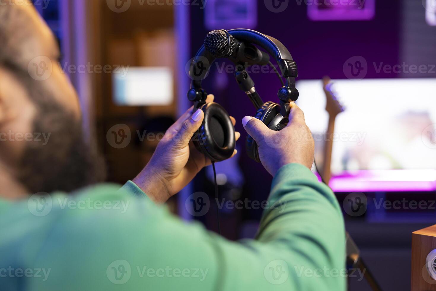 Professional sound engineer picking up his headphones for a recording session, applying mix and master techniques with digital software and stereo console. Skilled producer editing tracks. Close up. photo