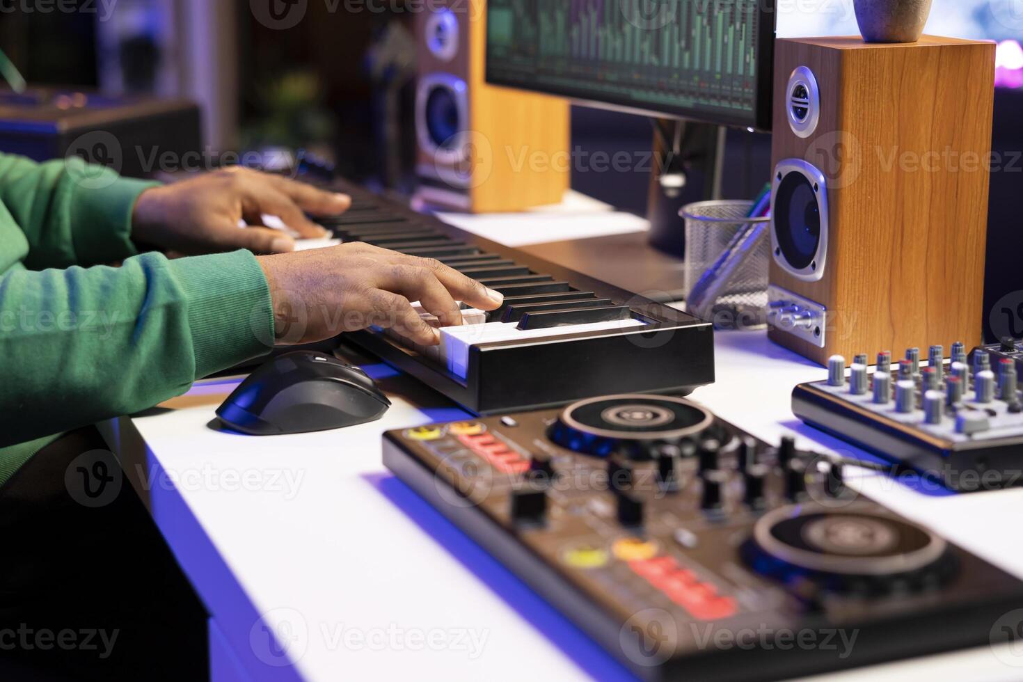 Music producer plays electronic keyboard piano notes over a recording in home studio, producing new tracks for an album. Artist technician mixing and mastering his own songs. Close up. photo