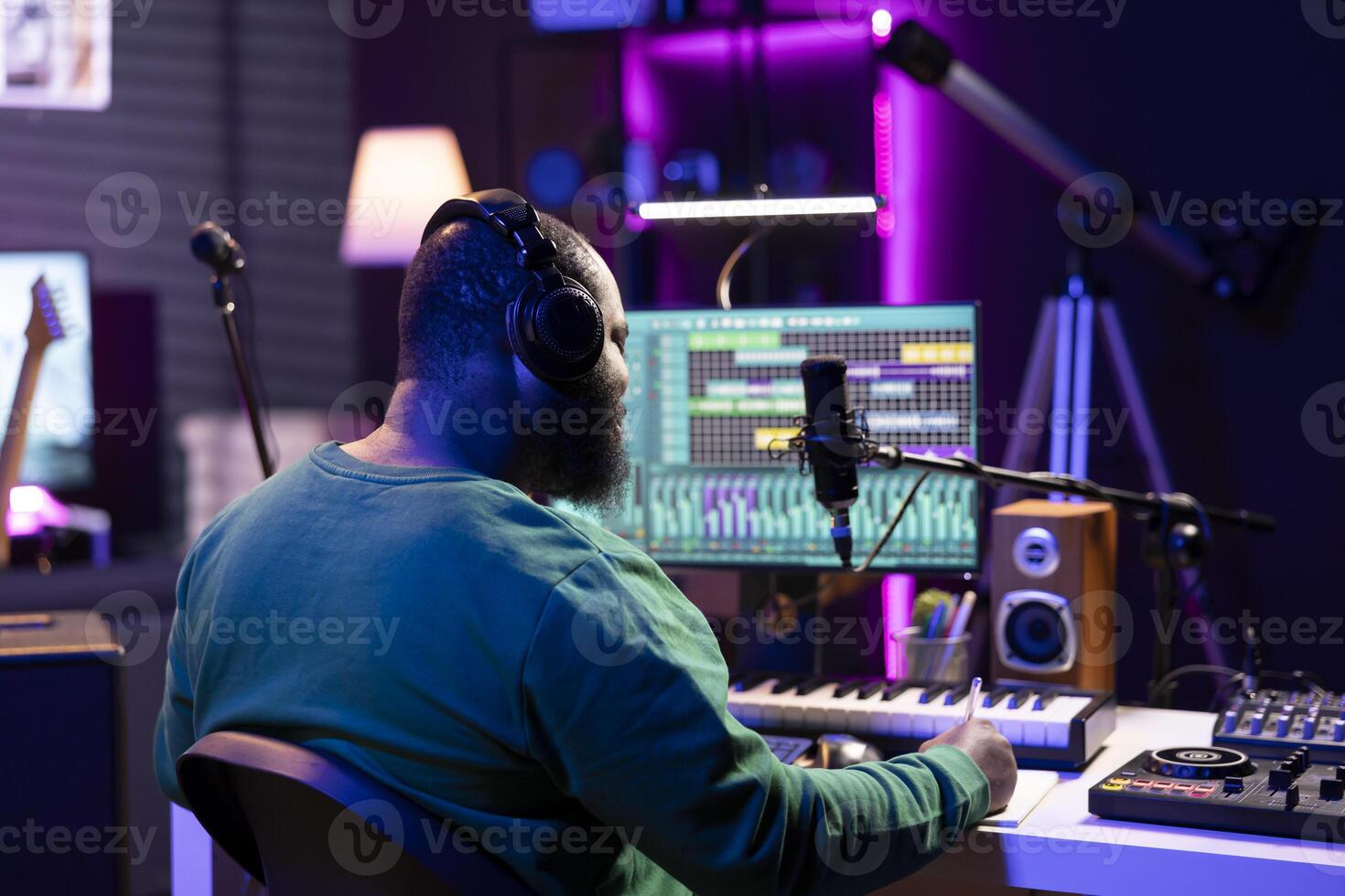 Young artist producer writing lyrics and musical notes to create new tracks in home studio, thinking about acoustics and lines for a modern cool soundtrack. Songwriter composing tracks with gear. photo