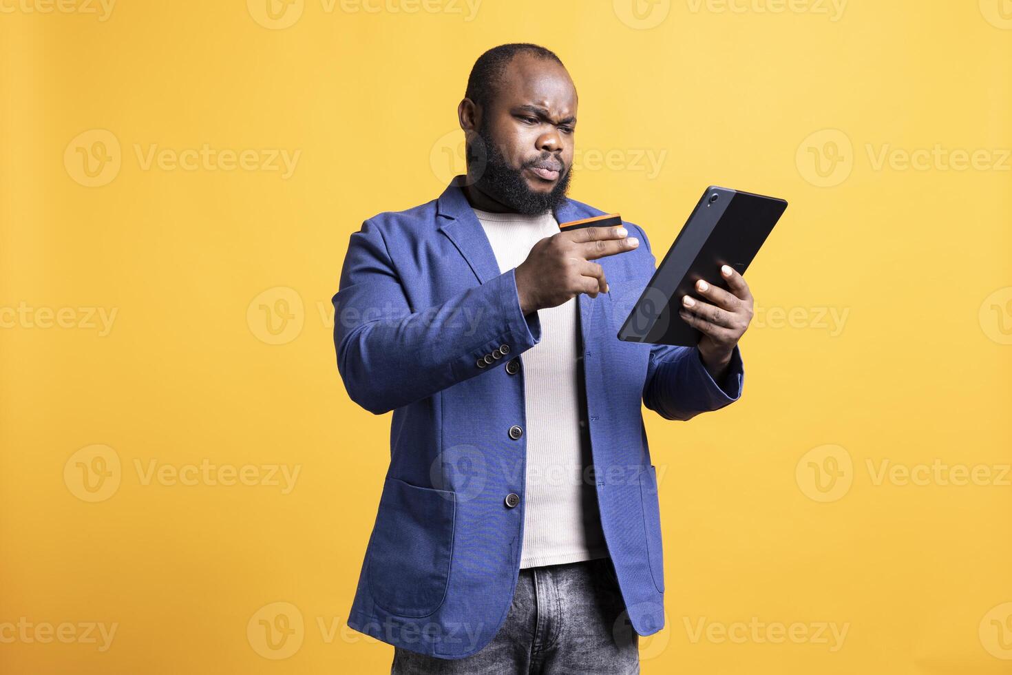 Man with frown on face while adding payment method on website, seeing insufficient funds error, studio background. Upset person getting transaction rejected, wrongly typing credit card data on tablet photo