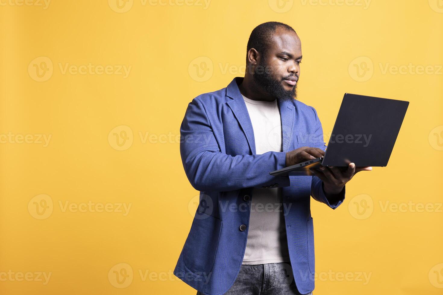 Man looking at business diagram and figures on laptop, isolated over studio background. BIPOC employee checking company financial annual report charts on notebook screen photo
