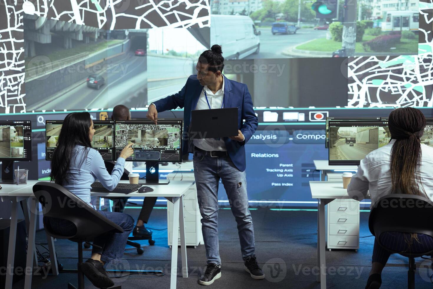 Indian coordinator offers instructions for his staff in control center monitoring room, following delivery trucks with gps coordinates on satellite map. Agency employees provide support for couriers. photo