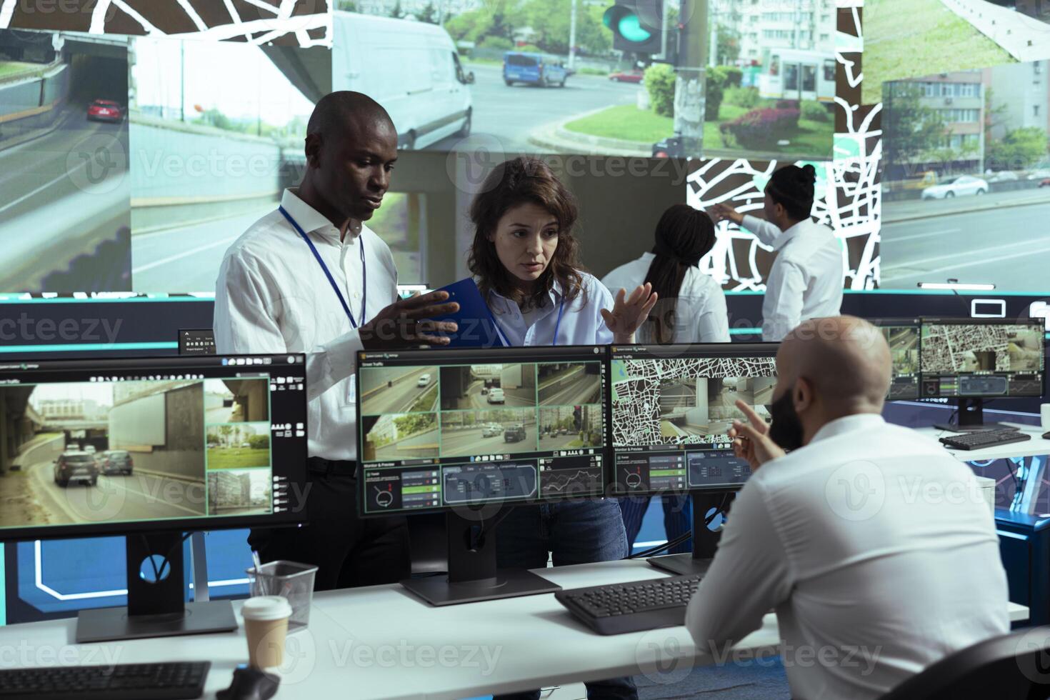 Diverse employees consulting each other on gps tracking activity, discussing about cargo logistics and express delivery. Sharing insight on satellite map location, CCTV surveillance footage. photo
