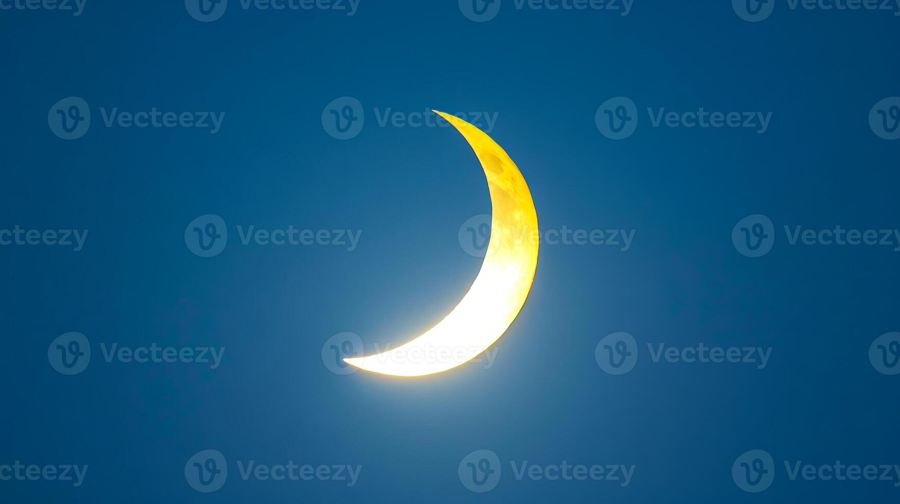 Crescent moon in a deep blue night sky. Curved moon among dark blue sky. Concept of astronomy, night time, serene sky, lunar phases photo