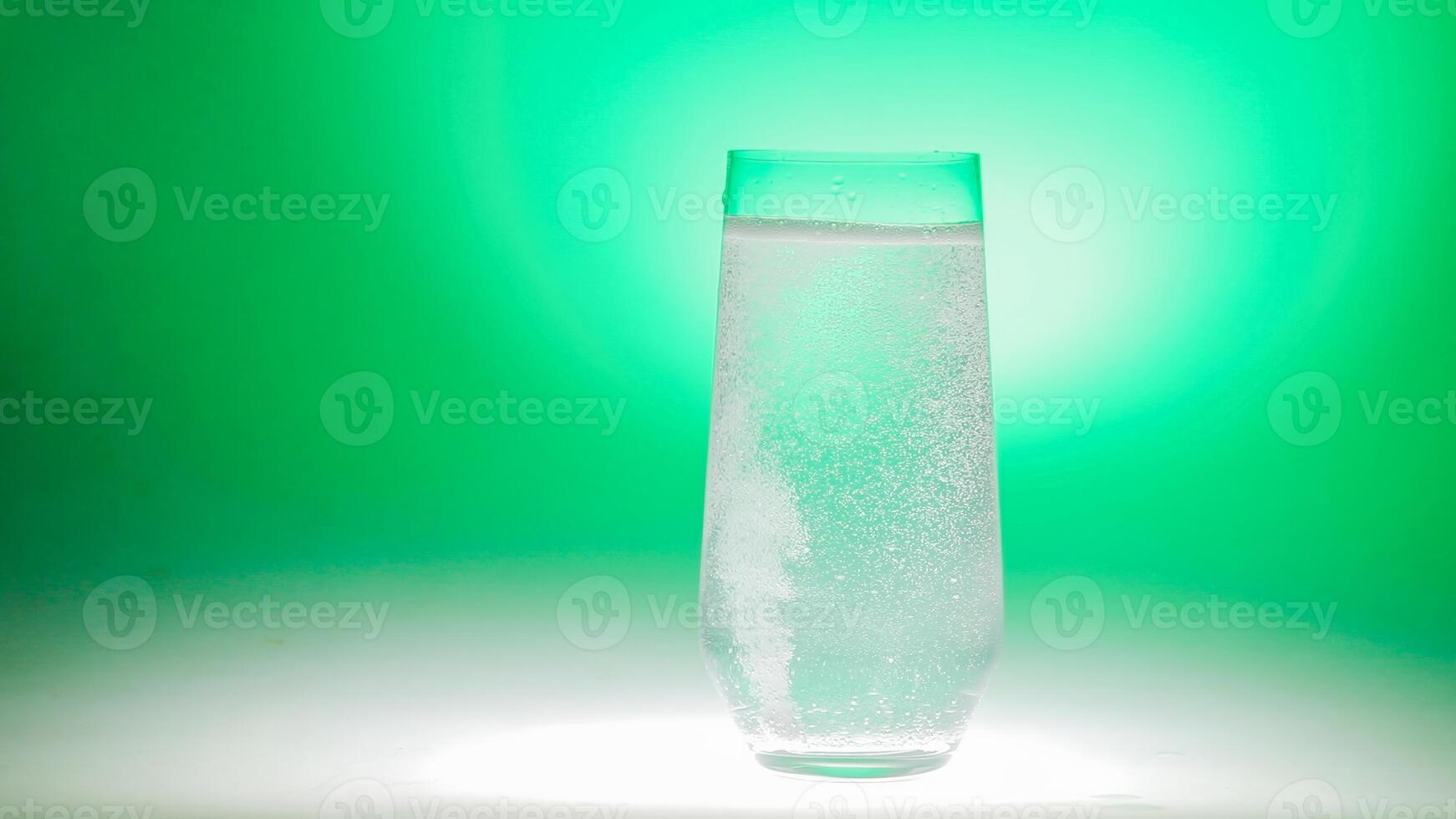 Effervescent water in a clear glass against a vibrant green backdrop, suggesting themes of refreshment, St Patricks Day celebrations, or healthy lifestyle concepts photo