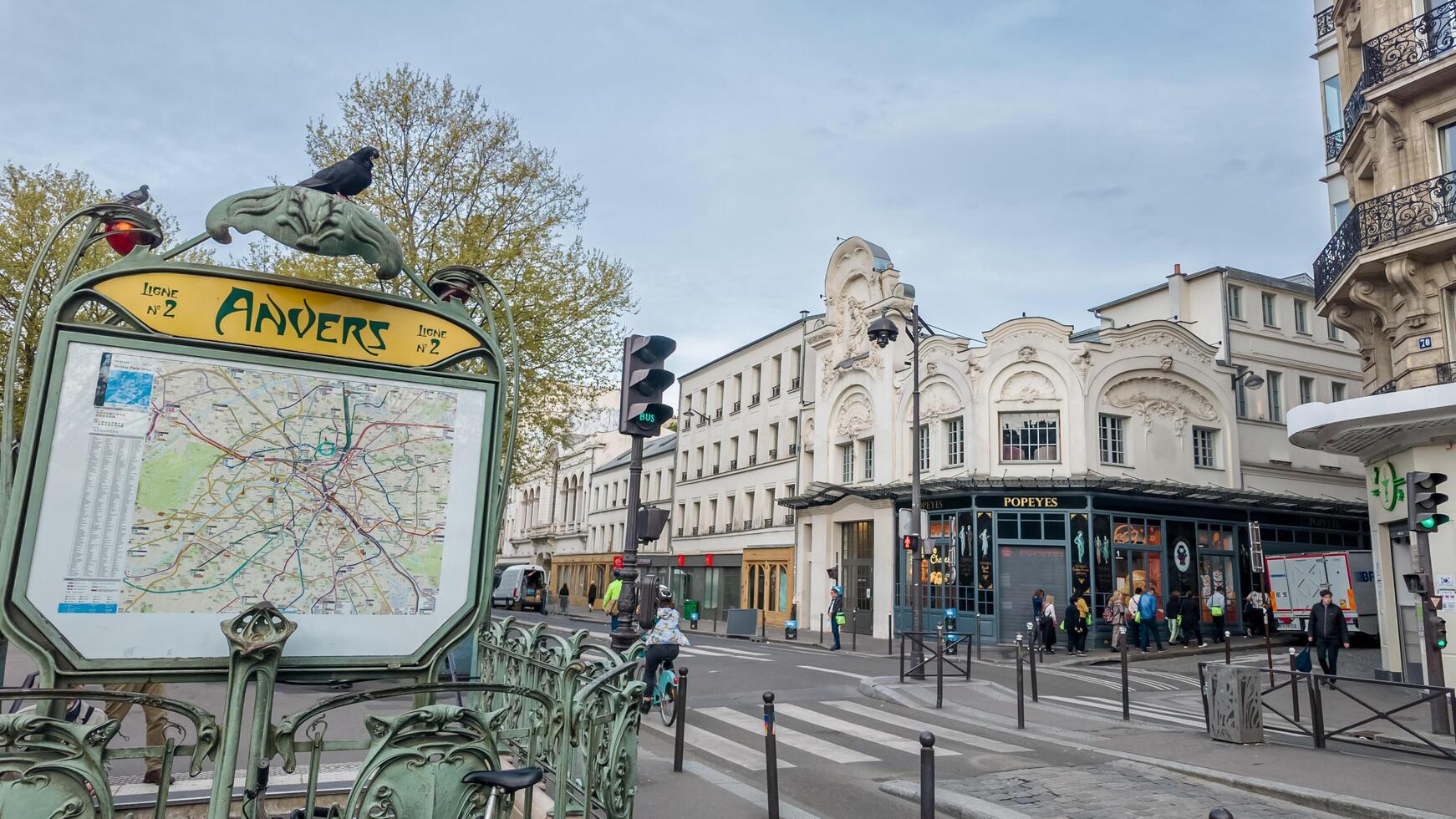 Iconic Parisian metro station with Art Nouveau map sign, bustling urban life, and springtime ambiance, captured in Paris, France, on April 14th, 2024 photo