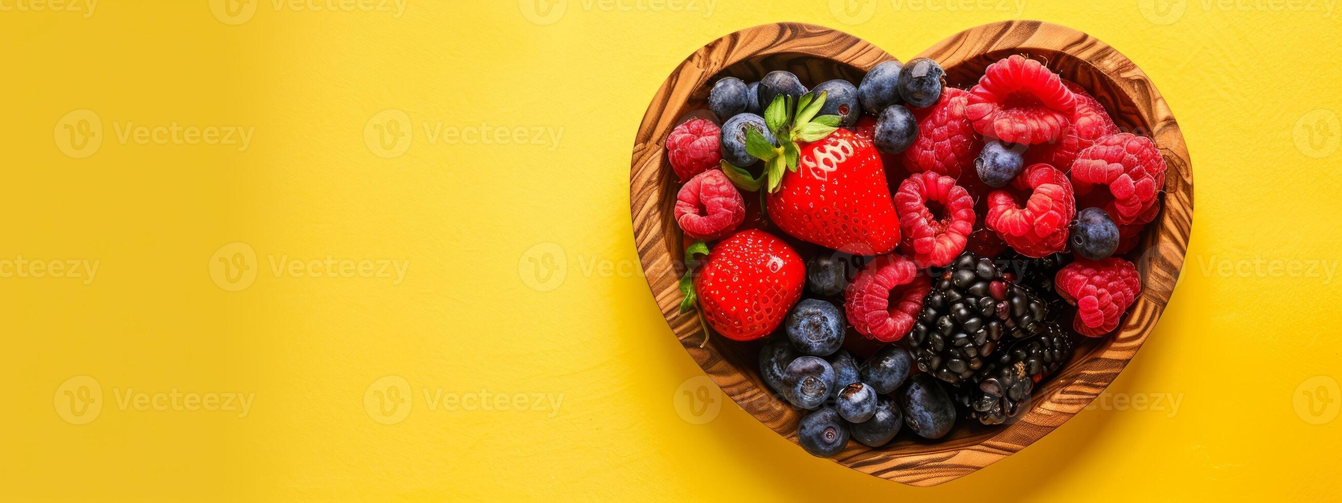 Heart-shaped wooden bowl filled with healthy fruits and vegetables. Fresh organic produce. Health, nutrition, diet, wellness concept. Banner. Copy space. Yellow background. Foods for healthy heart photo