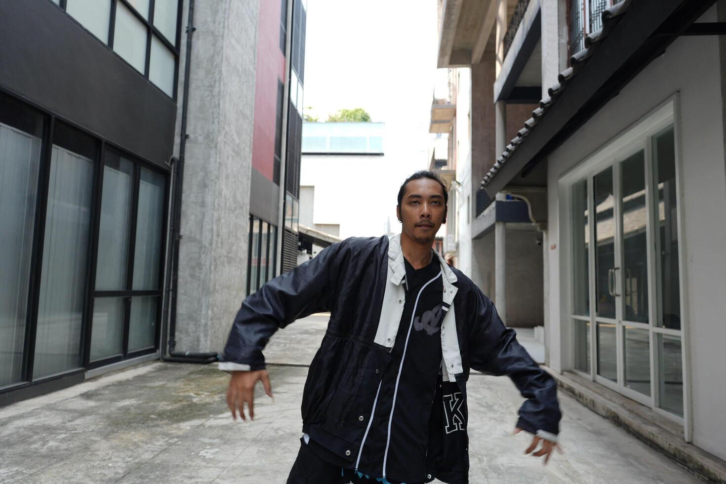 ASian man is dancing in hip hop style at outdoor space. Professional solo dancer is performing in public area. photo