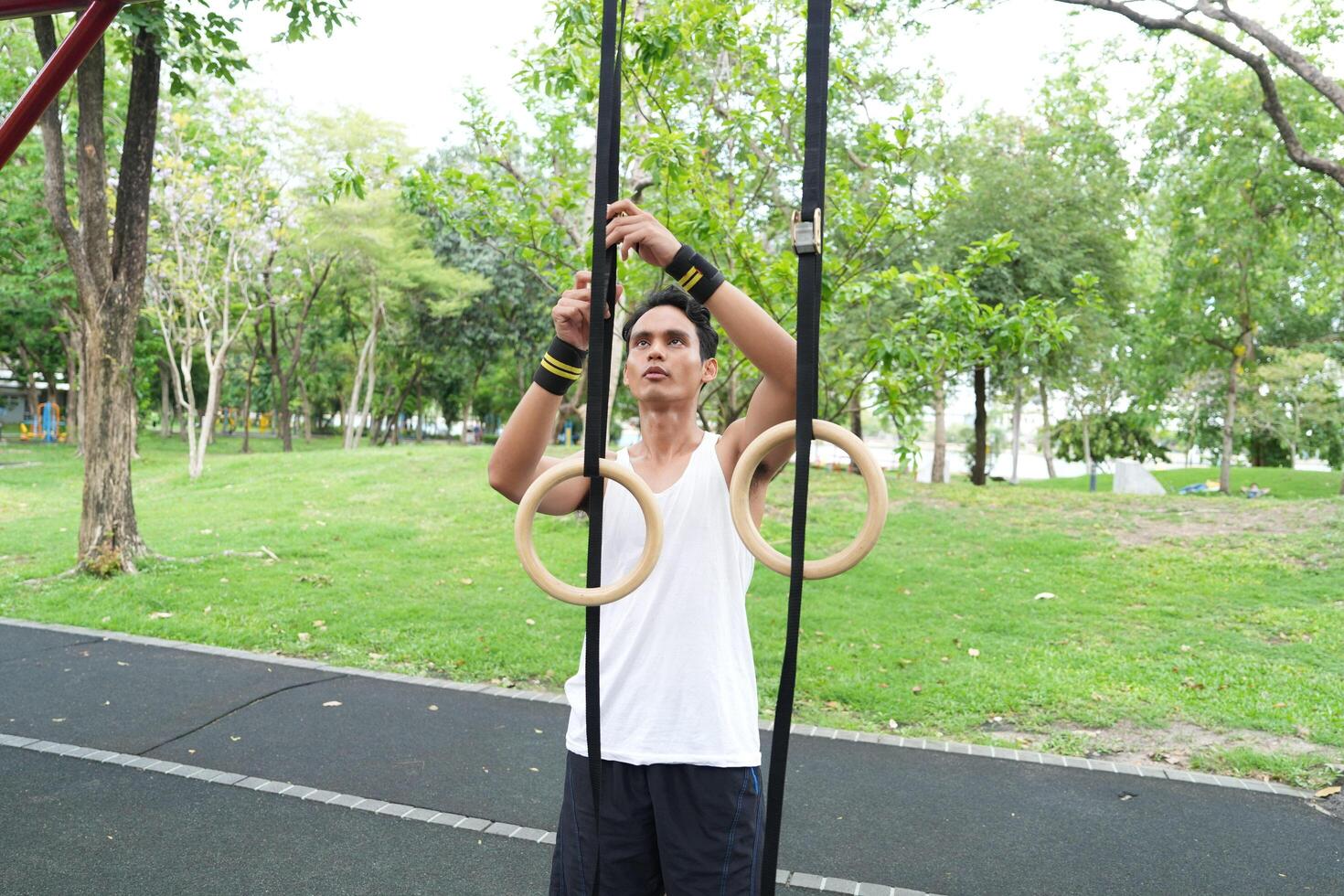 Asian man practicing gymnastics doing gymnastics bar and hoop exercises and stretching and resting for sports. photo
