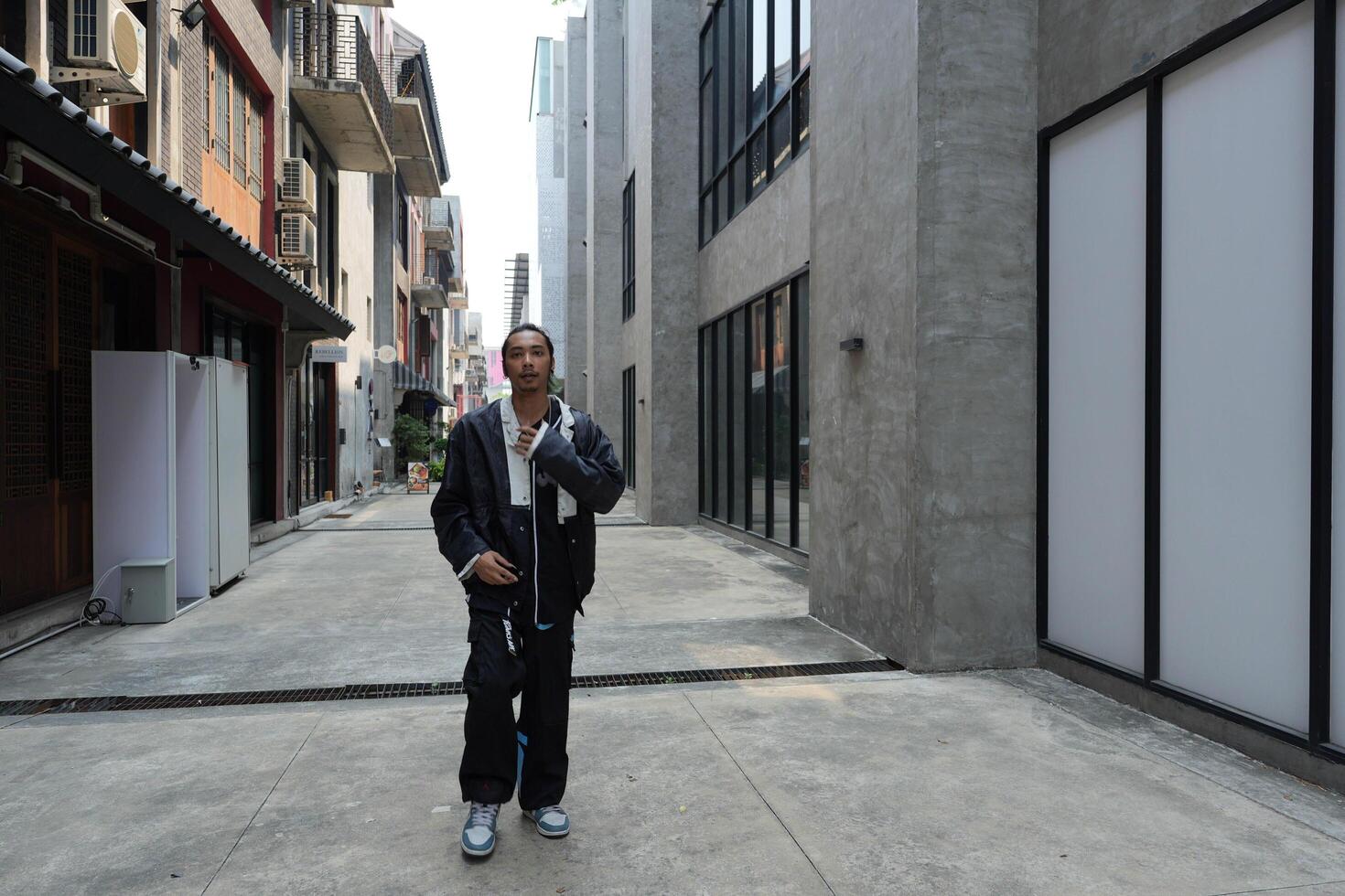ASian man is dancing in hip hop style at outdoor space. Professional solo dancer is performing in public area. photo