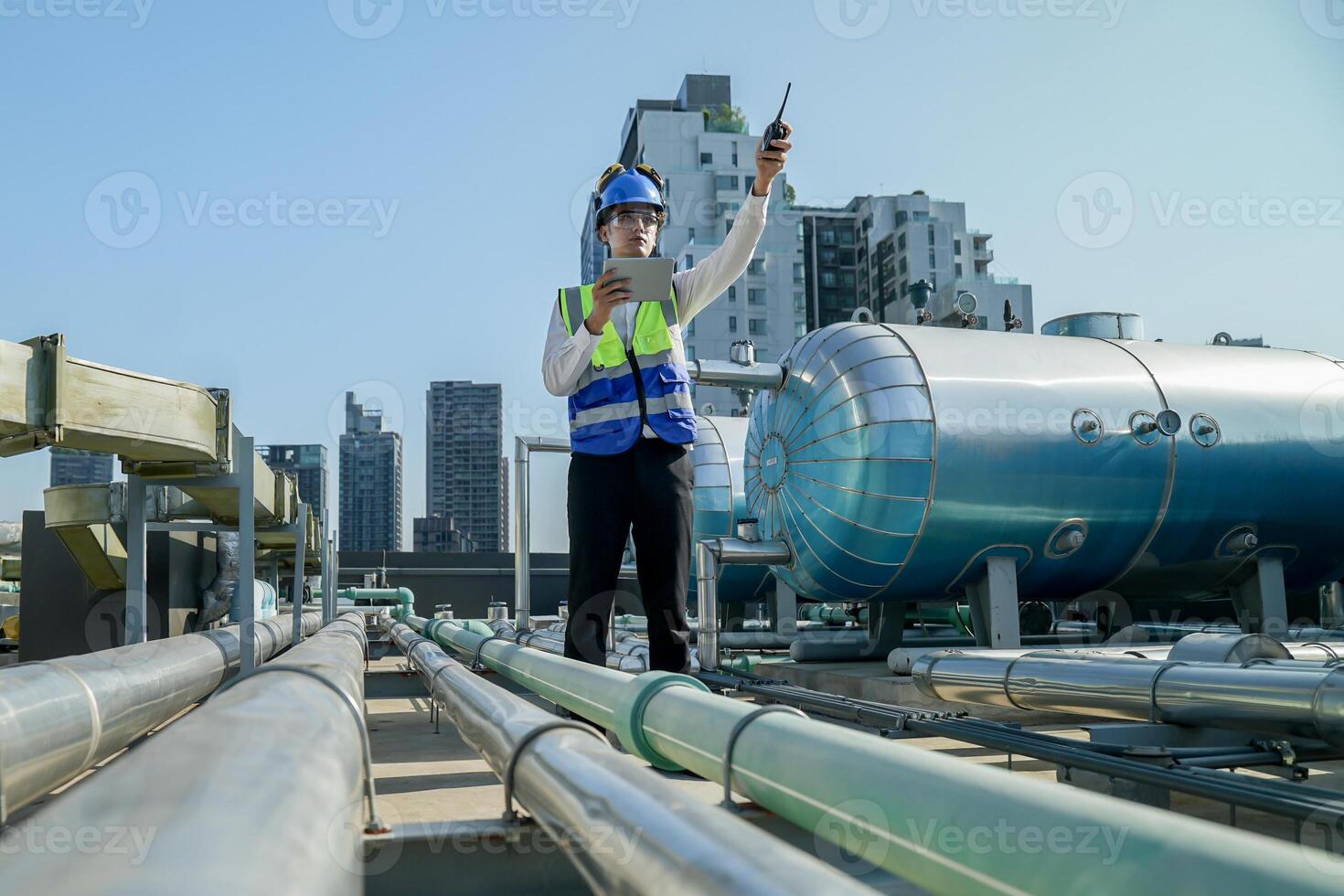 Urban rooftop scene showing a young engineer with a radio, inspecting and adjusting equipment in a sunny city environment. Safety and precision at work. photo