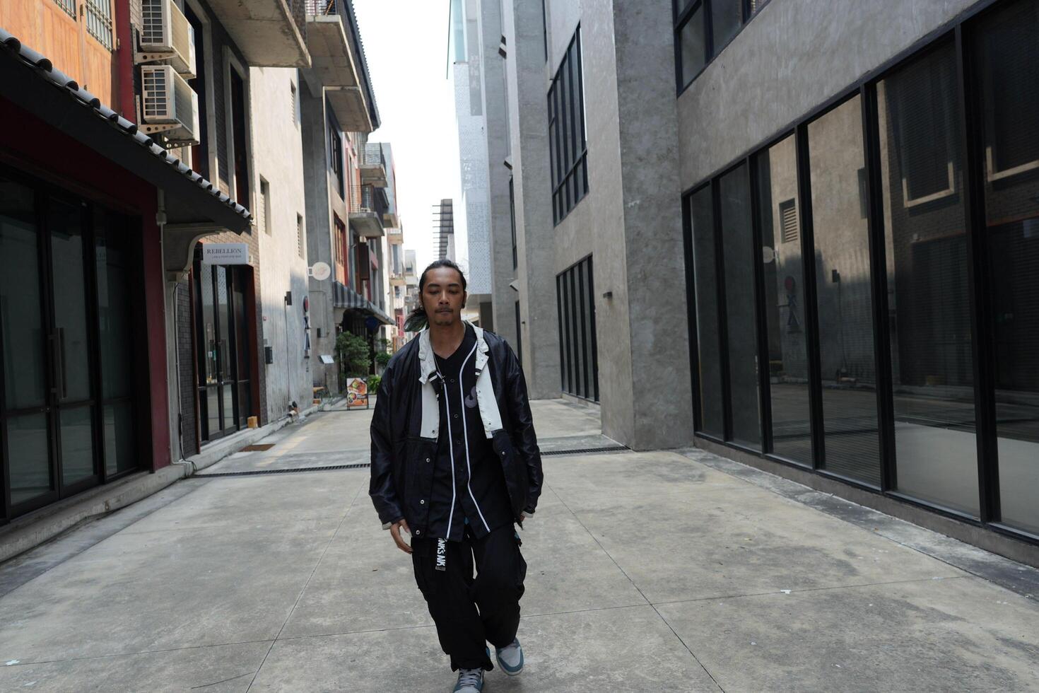 ASian man is dancing in hip hop style at outdoor space. Professional solo dancer is performing in public area. photo