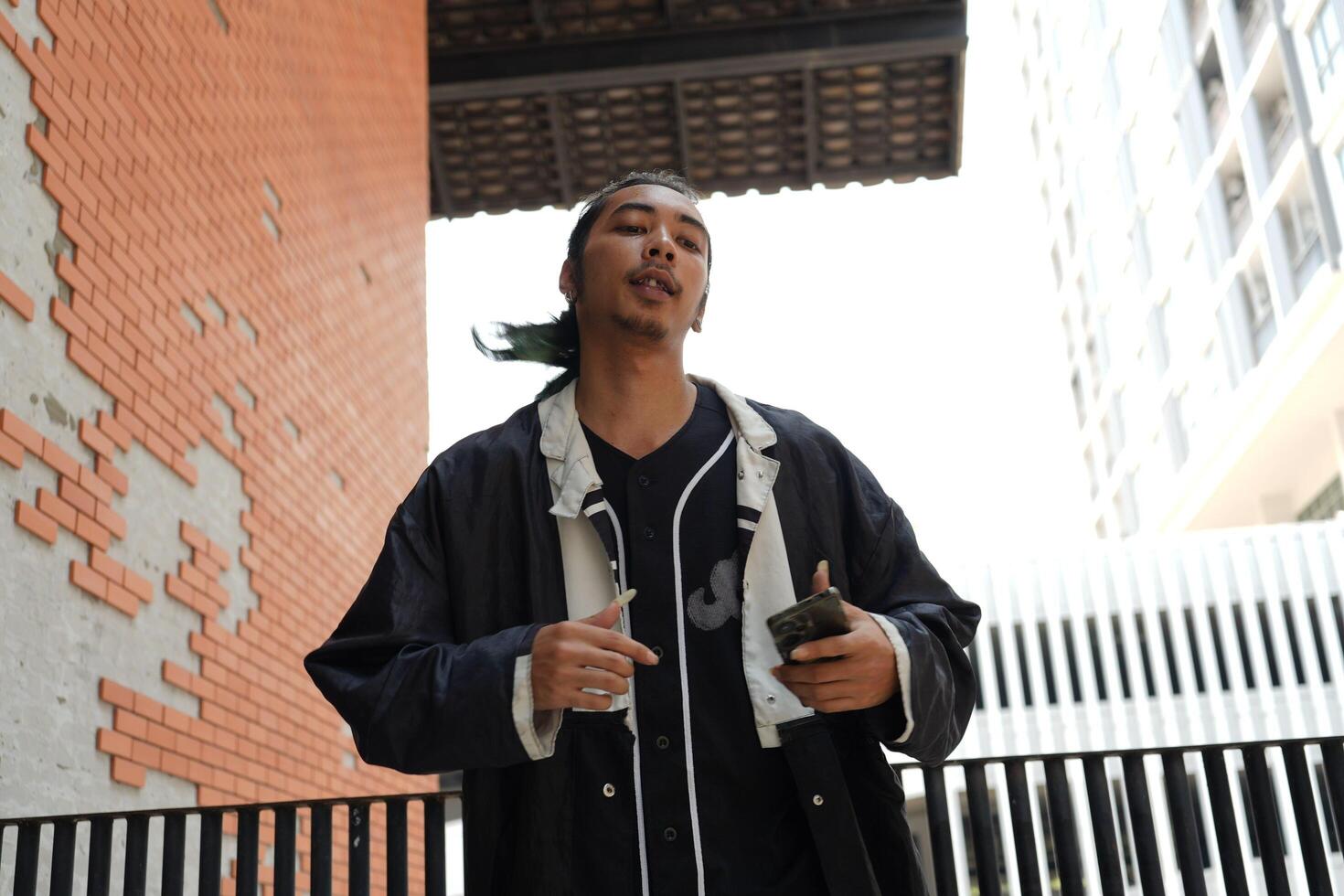 ASian man is dancing in hip hop style at outdoor space. Professional solo dancer is performing in public area. photo