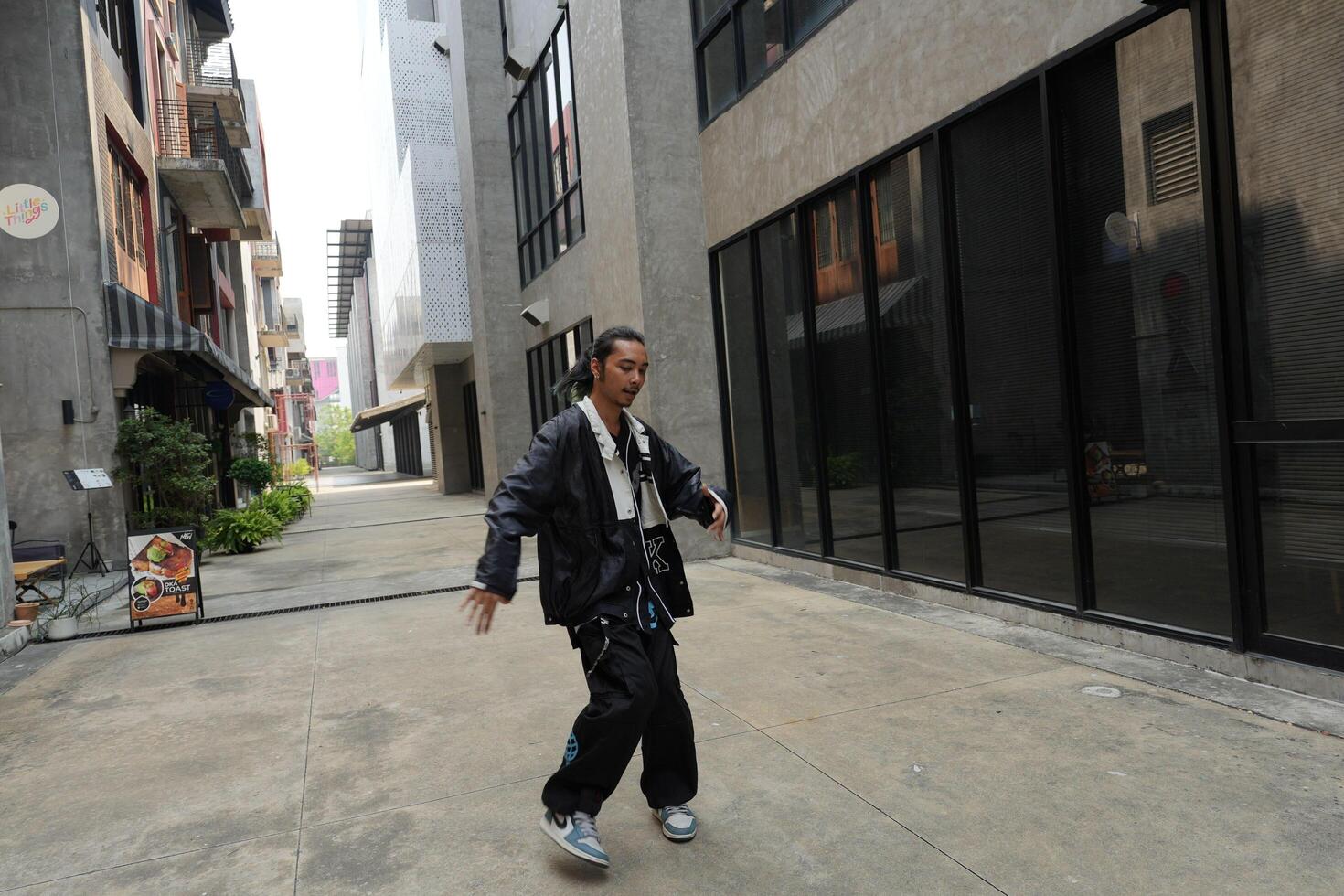 ASian man is dancing in hip hop style at outdoor space. Professional solo dancer is performing in public area. photo