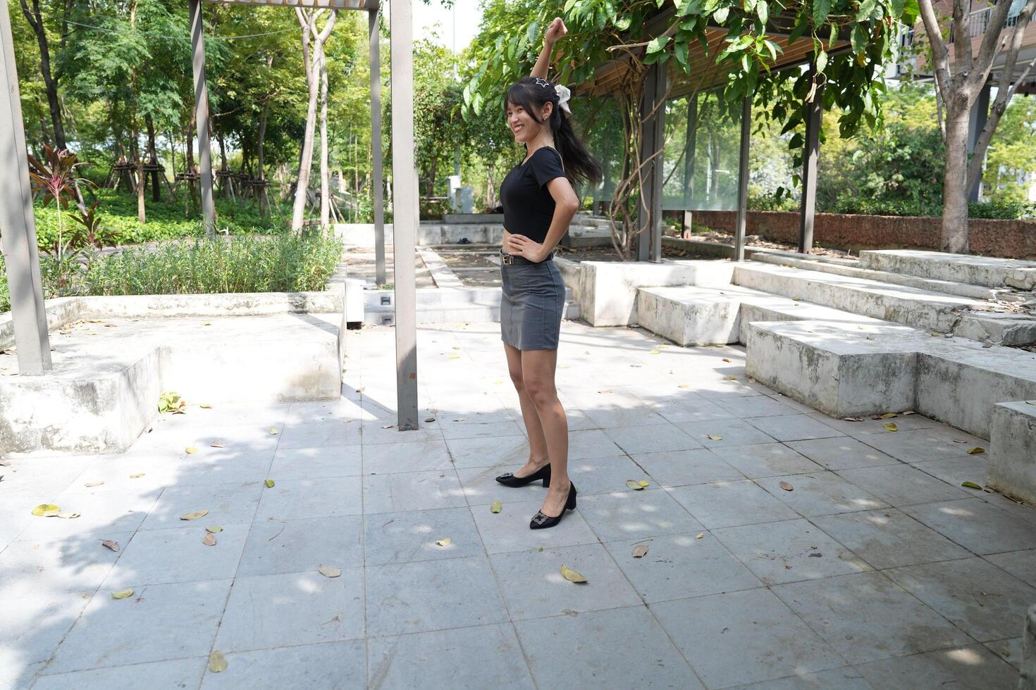 Asian woman dancing in the middle of a park photo