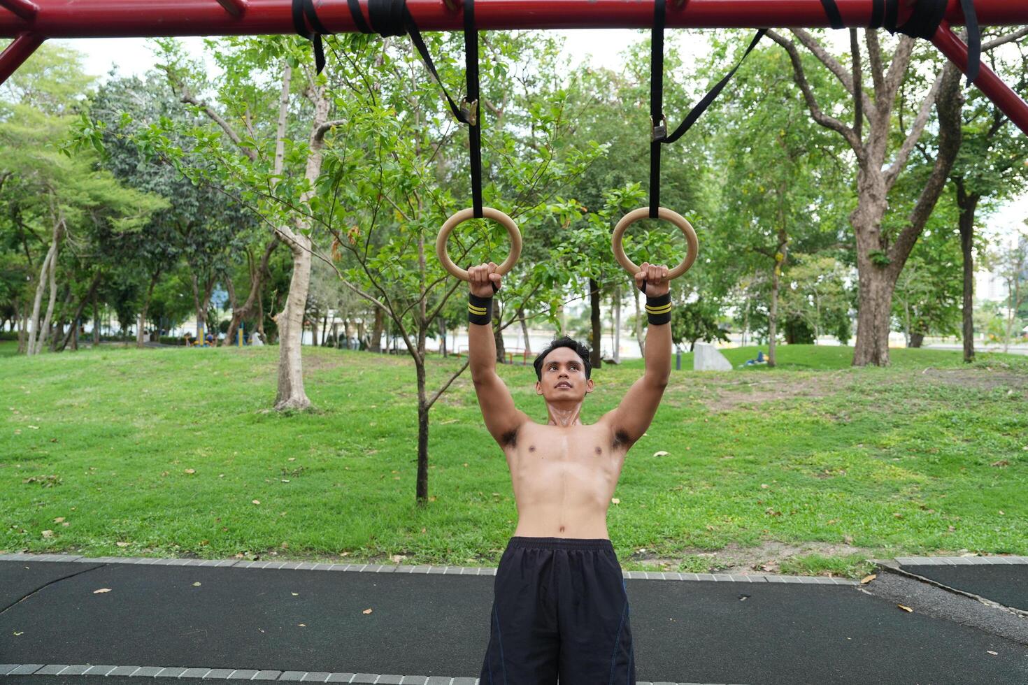 Asian man practicing gymnastics, doing gymnastics bar and hoop exercises and stretching, resting for sports. photo