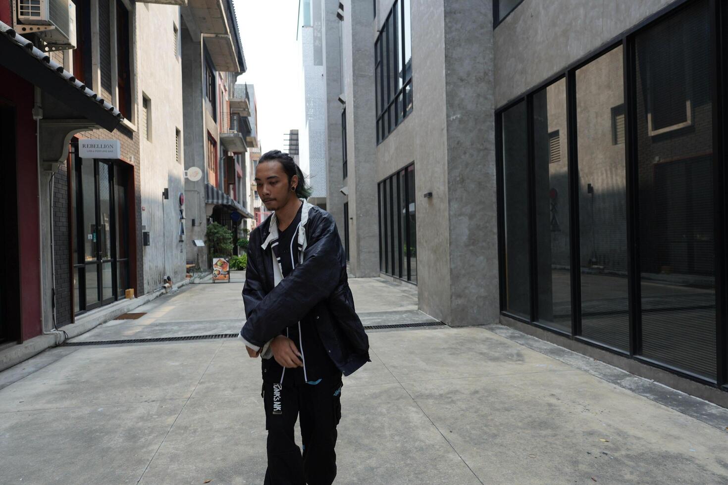 ASian man is dancing in hip hop style at outdoor space. Professional solo dancer is performing in public area. photo