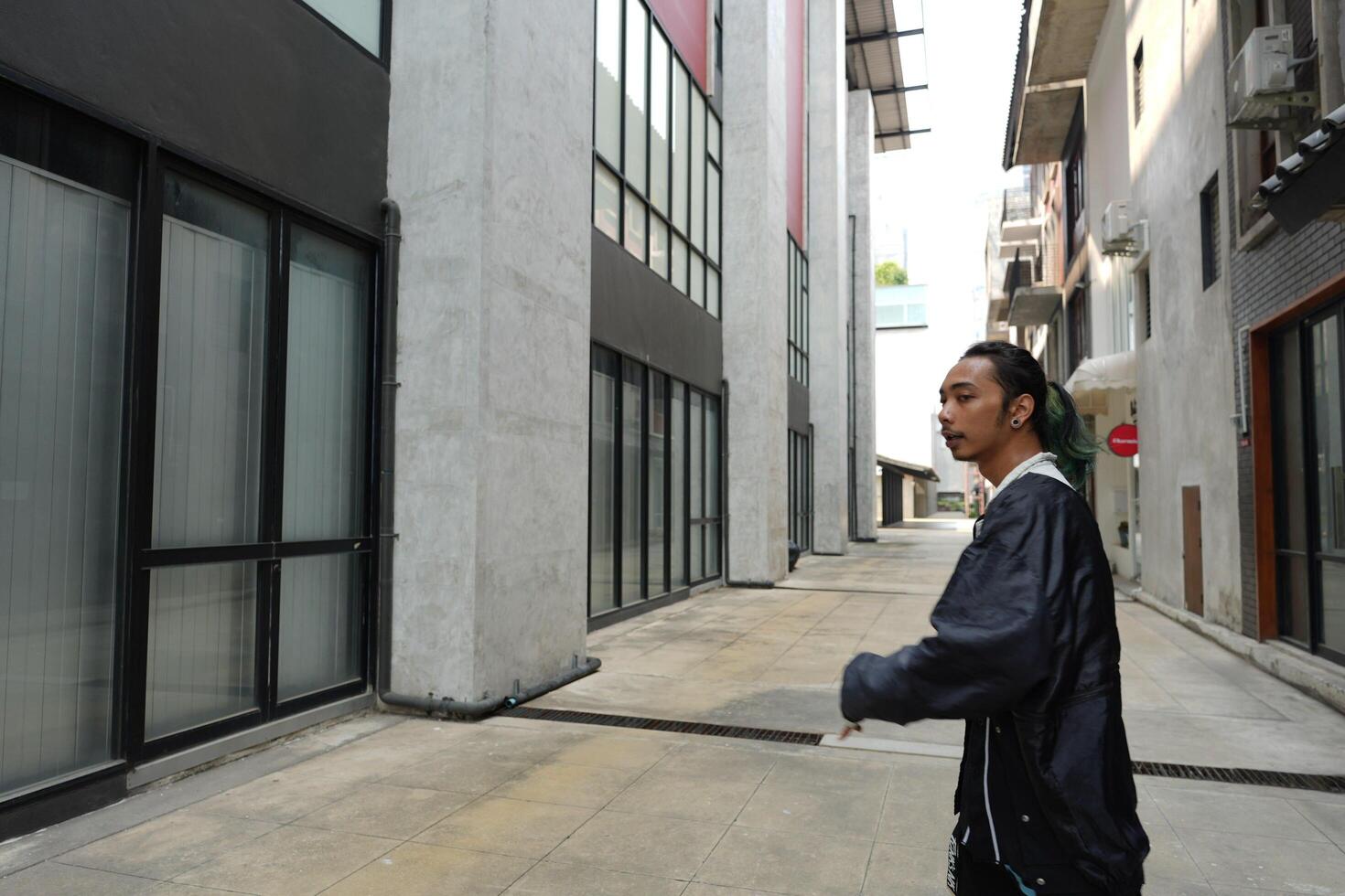ASian man is dancing in hip hop style at outdoor space. Professional solo dancer is performing in public area. photo