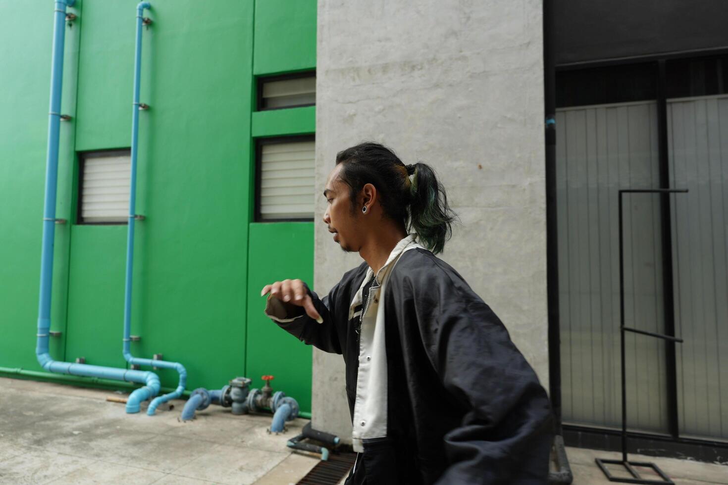 ASian man is dancing in hip hop style at outdoor space. Professional solo dancer is performing in public area. photo