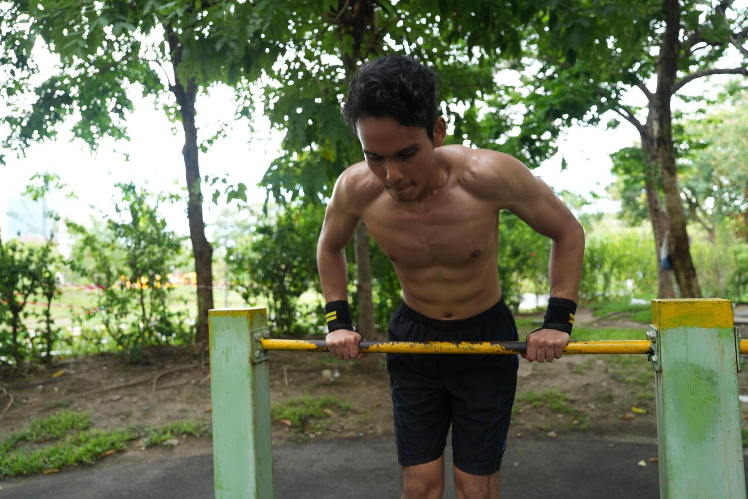 Asian man practicing gymnastics, doing gymnastics bar and hoop exercises and stretching, resting for sports. photo