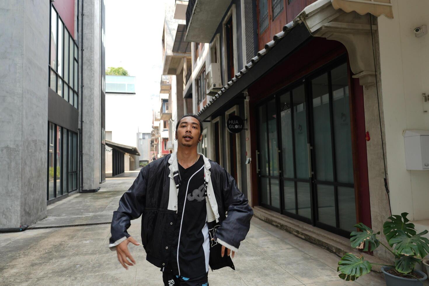 ASian man is dancing in hip hop style at outdoor space. Professional solo dancer is performing in public area. photo