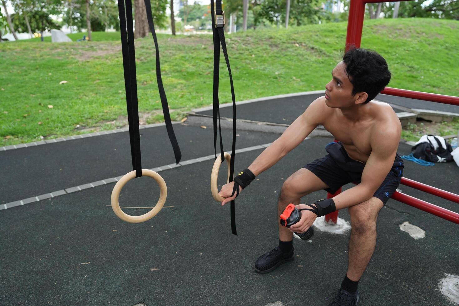 Asian man practicing gymnastics, doing gymnastics bar and hoop exercises and stretching, resting for sports. photo