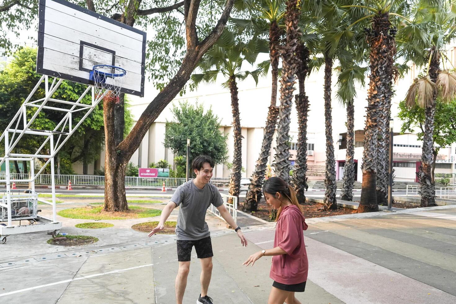 The male and female basketball players practice using the ball in the park court diligently and happily. photo