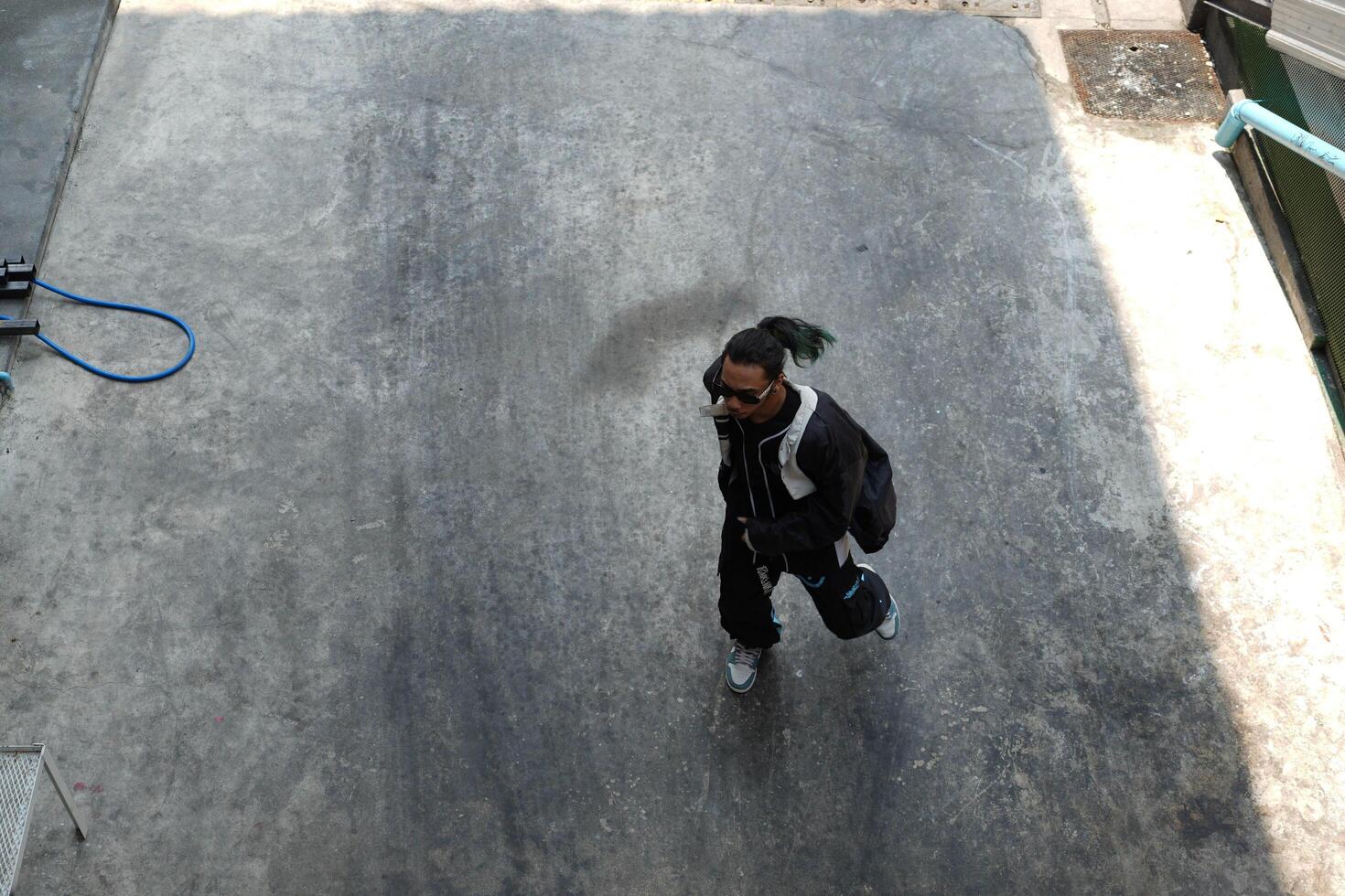 ASian man is dancing in hip hop style at outdoor space. Professional solo dancer is performing in public area. photo