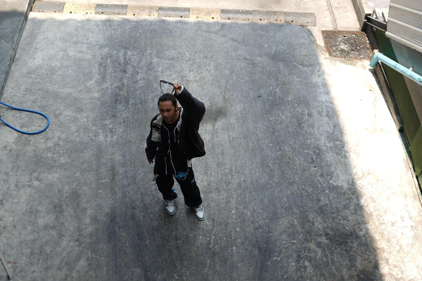 ASian man is dancing in hip hop style at outdoor space. Professional solo dancer is performing in public area. photo