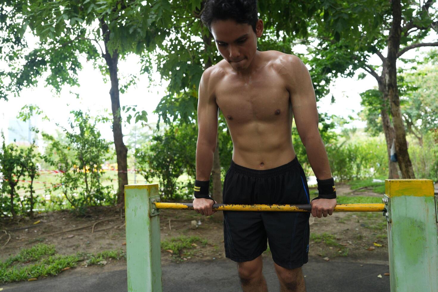 Asian man practicing gymnastics, doing gymnastics bar and hoop exercises and stretching, resting for sports. photo