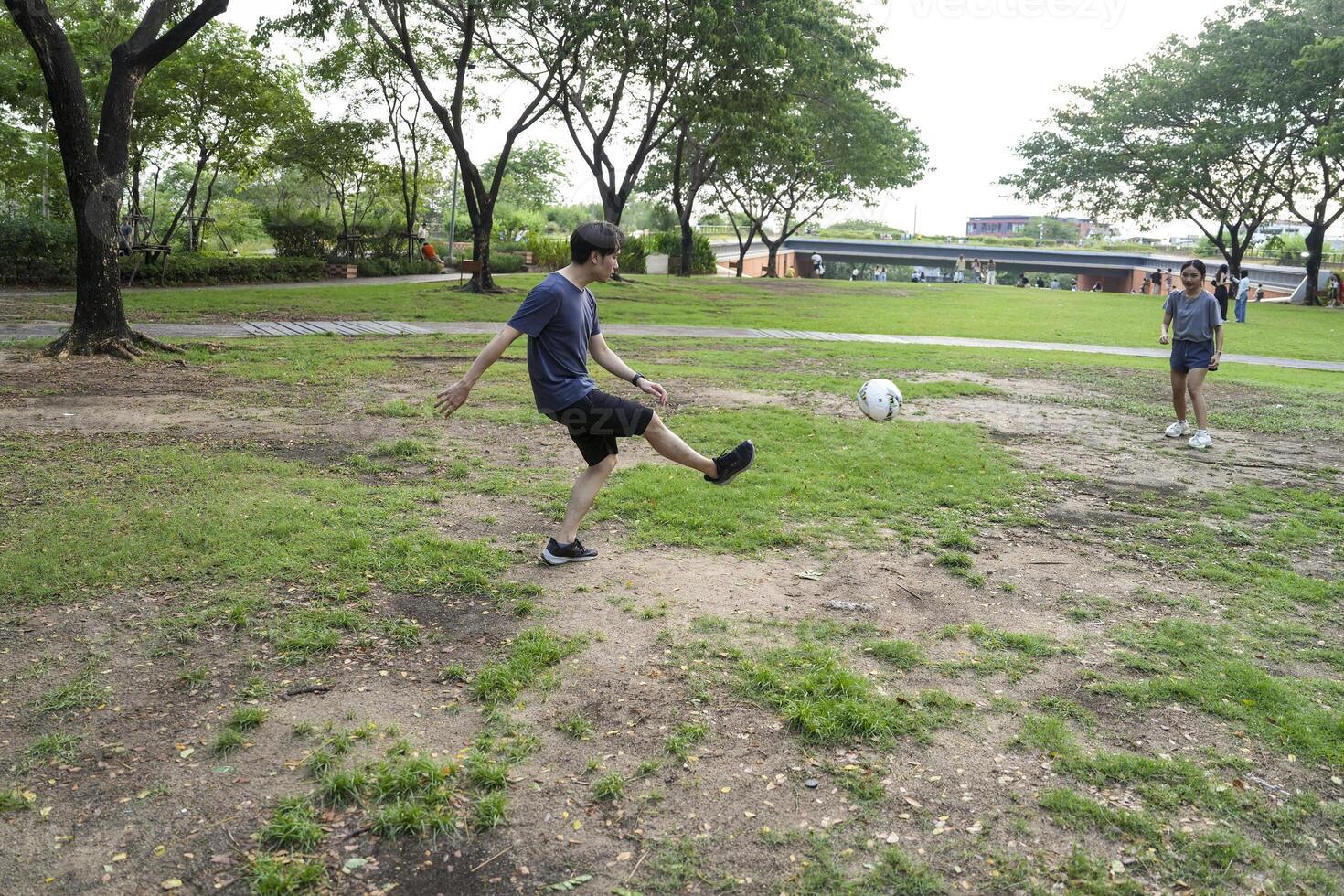 Asian man and woman are kicking and warming up before playing in soccer at outdoor park. photo