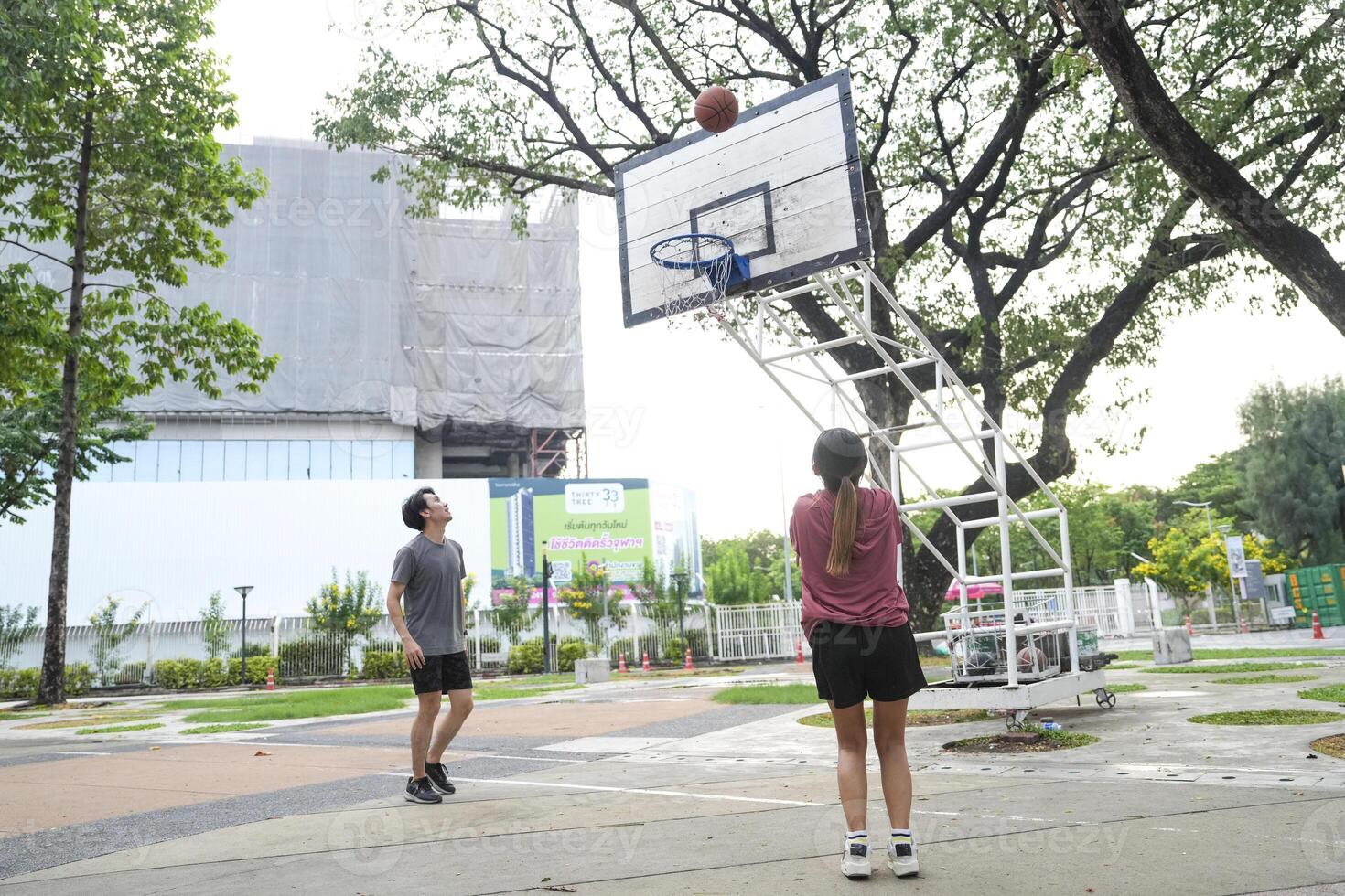The male and female basketball players practice using the ball in the park court diligently and happily. photo