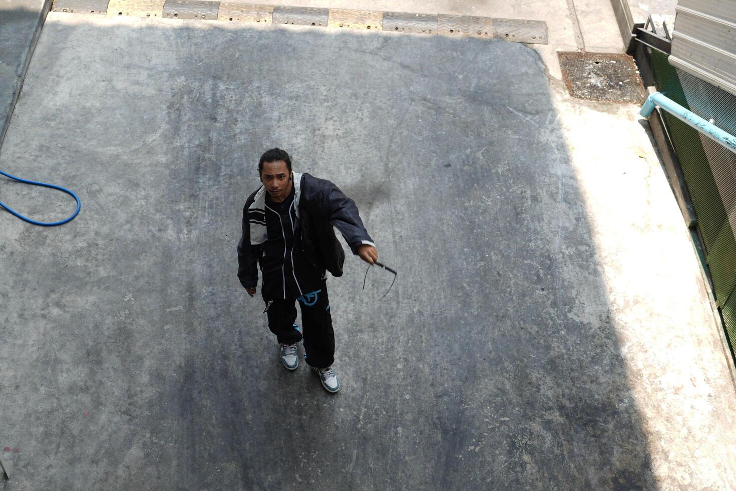 ASian man is dancing in hip hop style at outdoor space. Professional solo dancer is performing in public area. photo