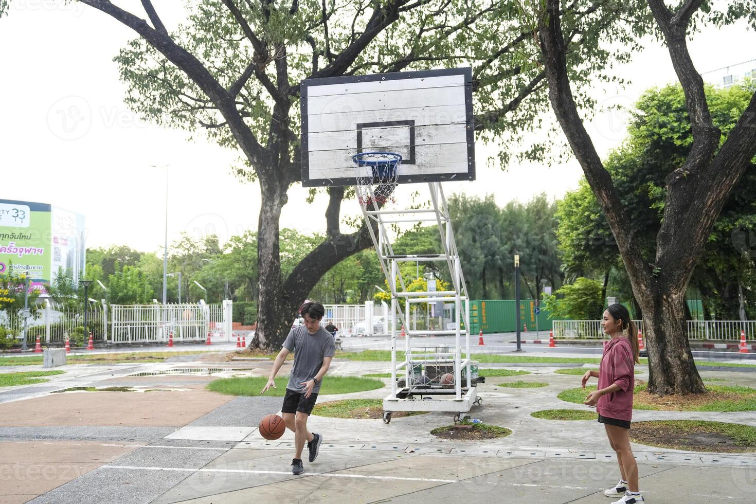 The male and female basketball players practice using the ball in the park court diligently and happily. photo