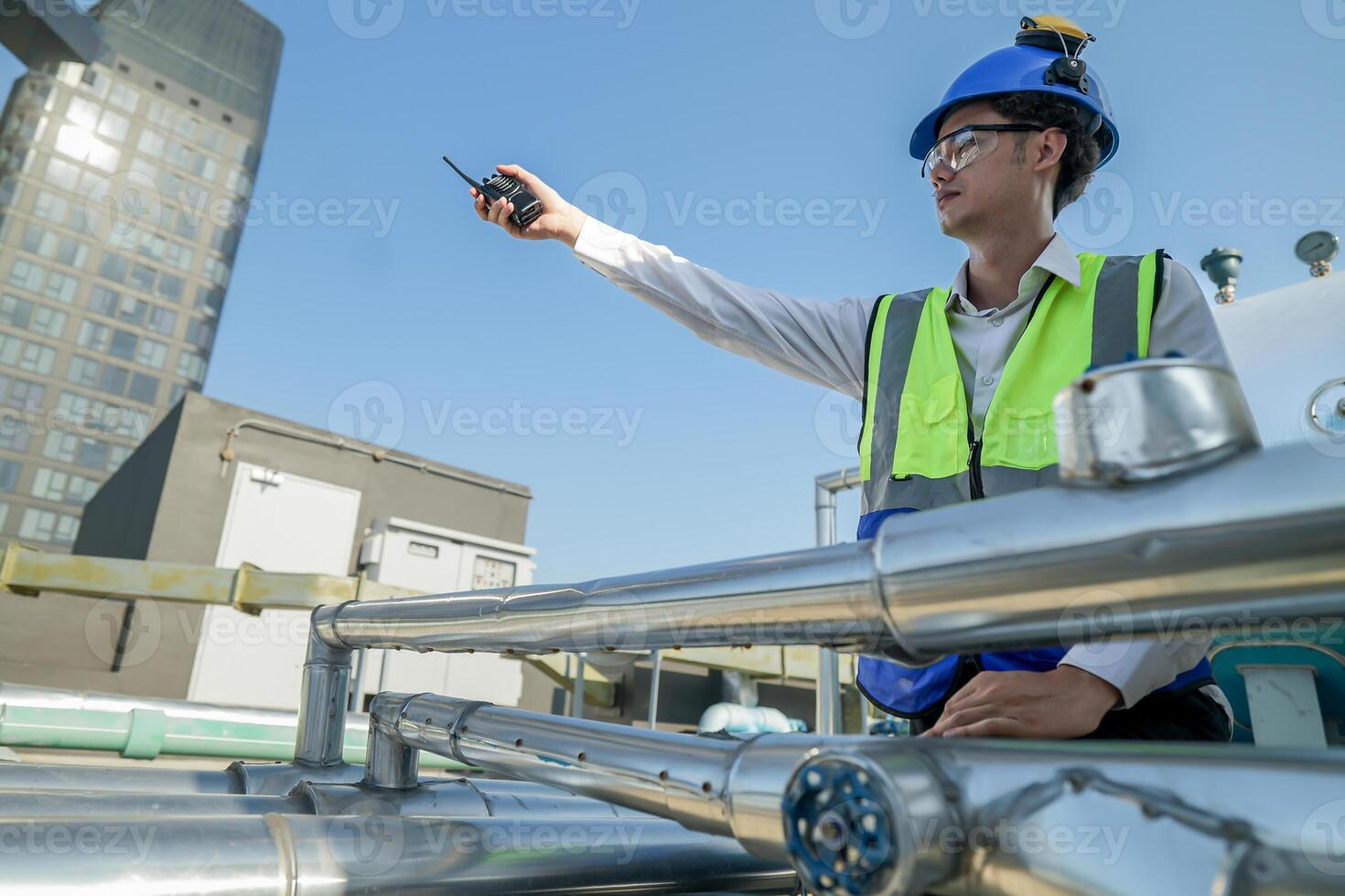 Urban rooftop scene showing a young engineer with a radio, inspecting and adjusting equipment in a sunny city environment. Safety and precision at work. photo