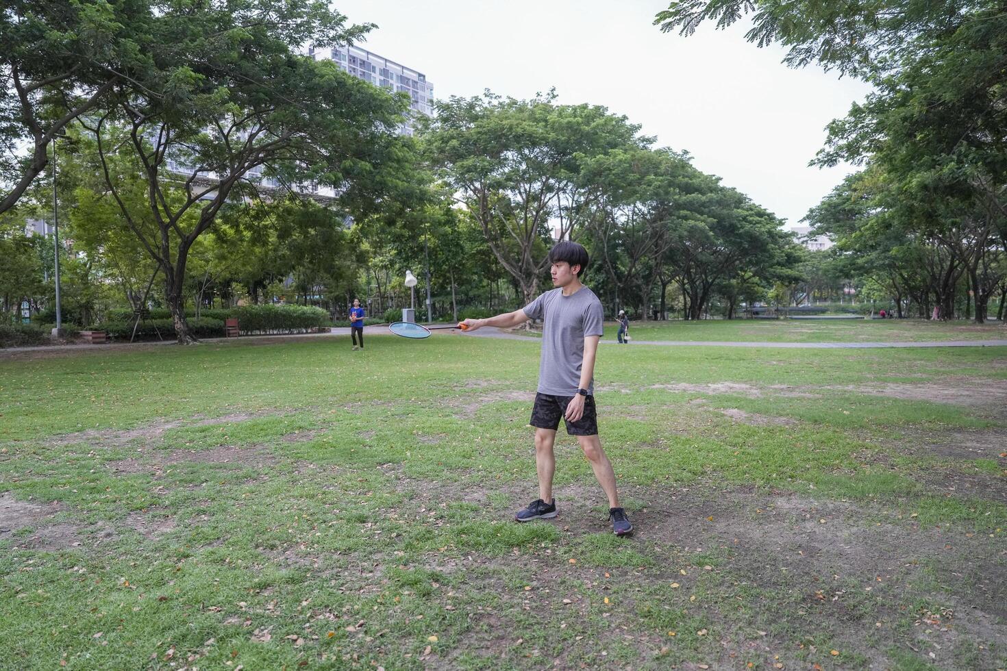Young people play badminton and repair diligently in the park area. photo