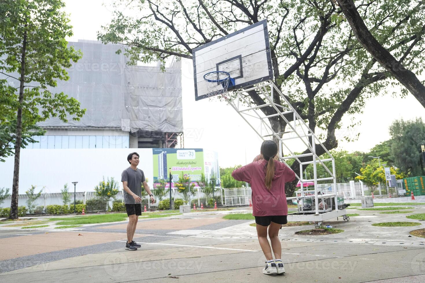 The male and female basketball players practice using the ball in the park court diligently and happily. photo