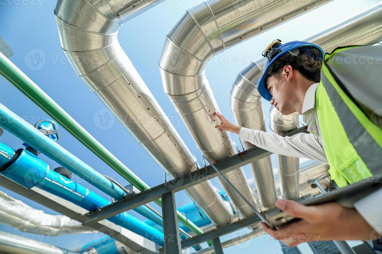 Industrial engineer adjusting pipeline valve with radio communication on construction site. Engineer on urban construction site using radio to coordinate with team on a sunny industrial rooftop. photo