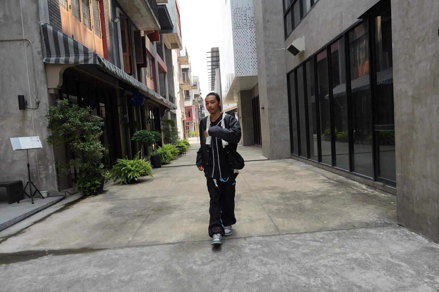 ASian man is dancing in hip hop style at outdoor space. Professional solo dancer is performing in public area. photo