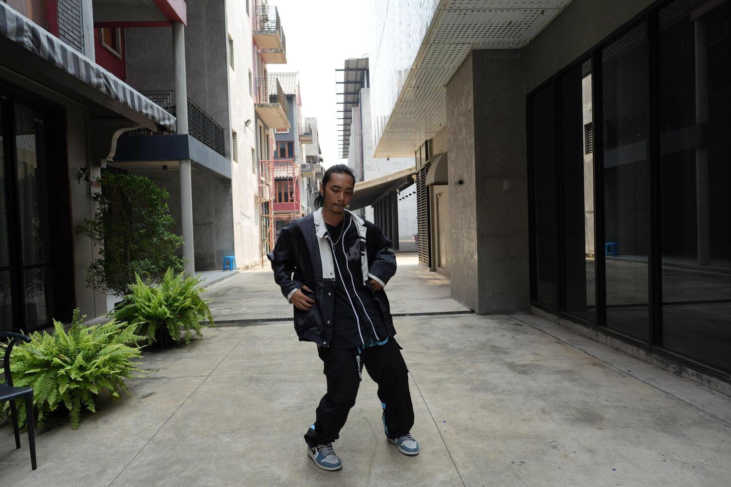 ASian man is dancing in hip hop style at outdoor space. Professional solo dancer is performing in public area. photo