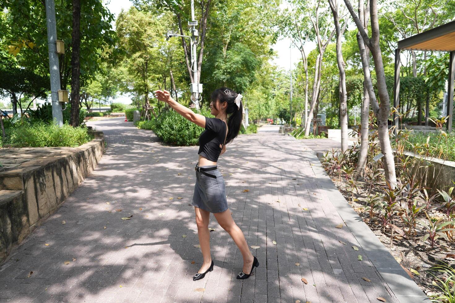 Asian woman dancing in the middle of a park photo