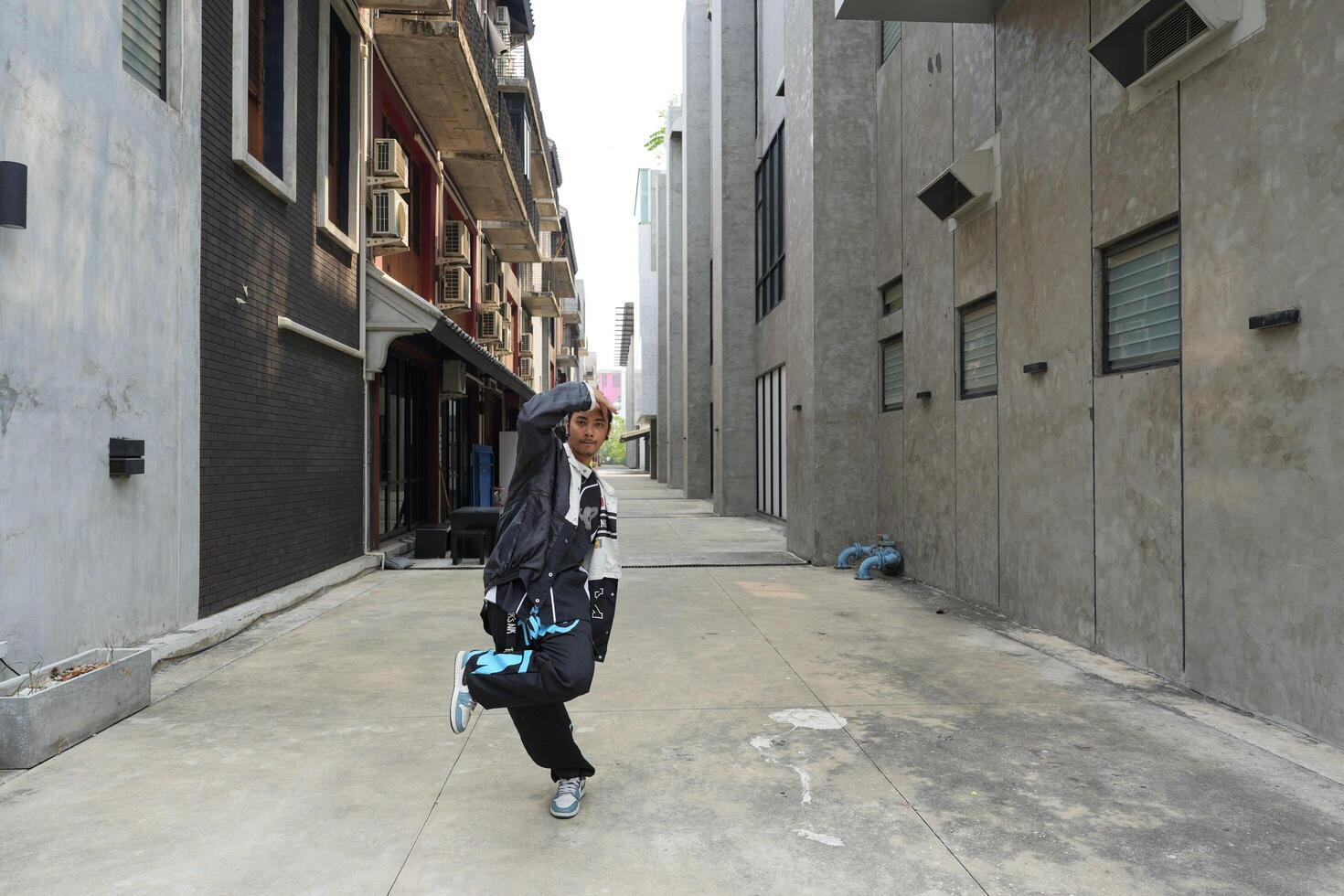 ASian man is dancing in hip hop style at outdoor space. Professional solo dancer is performing in public area. photo