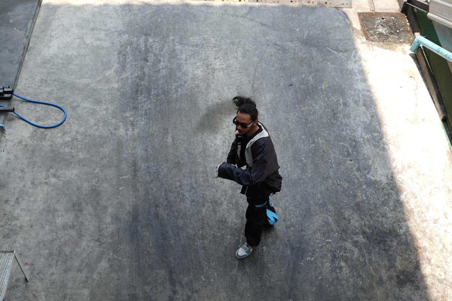 ASian man is dancing in hip hop style at outdoor space. Professional solo dancer is performing in public area. photo